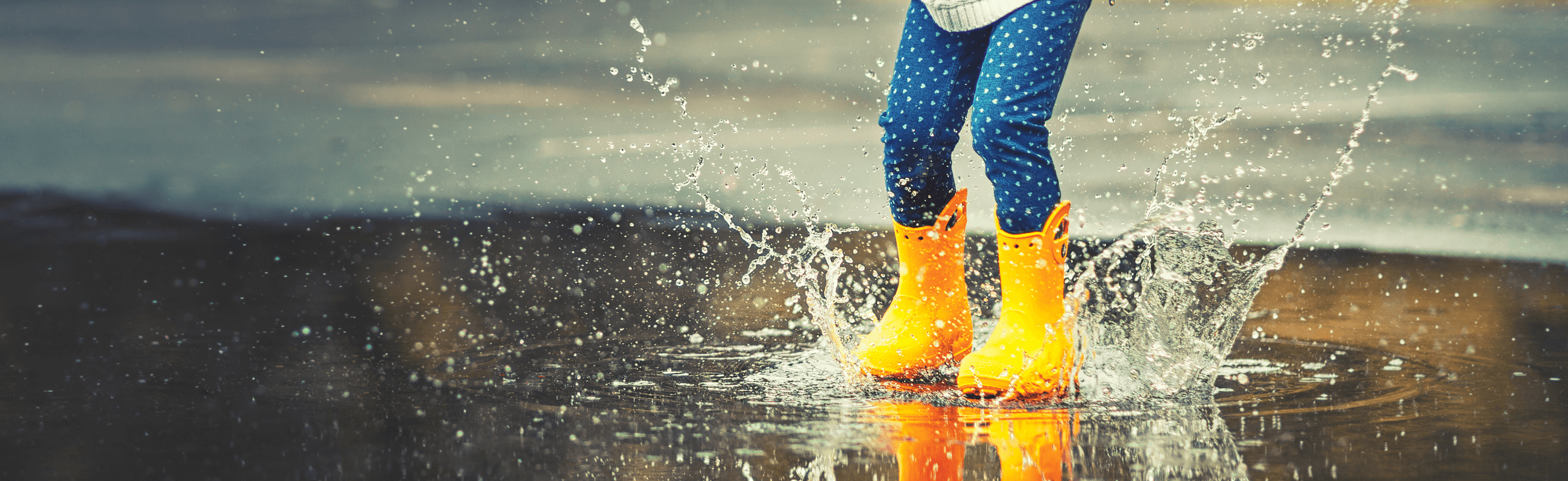 Photograph of a child splashing in a puddle